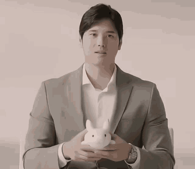 a man in a suit and white shirt is holding a stuffed rabbit
