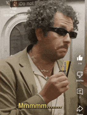 a man wearing sunglasses holds a credit card and says " mmmmm "
