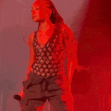 a woman is standing on a stage holding a microphone and dancing .