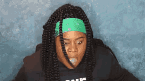 a woman with braids wearing a green bandana and a hoodie that says one