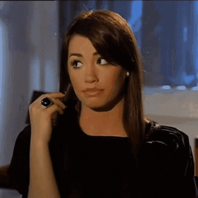 a woman wearing a black shirt and a black ring on her finger