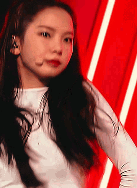 a woman with long black hair is wearing a white shirt and has a microphone in her mouth