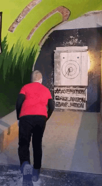 a man in a red shirt is standing in front of a target that says peace nation