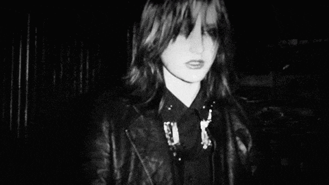 a black and white photo of a young girl wearing a leather jacket and a black shirt .
