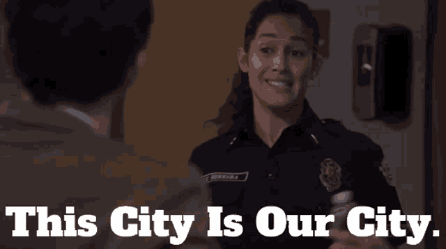 a woman in a police uniform talking to a man with the words this city is our city