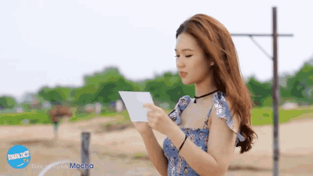 a woman holding a piece of paper in front of a banner that says " mocha " on it