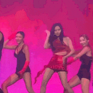 a woman in a red dress is dancing on a stage with another woman .