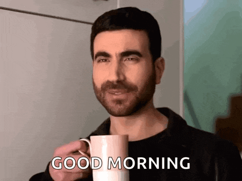 a man is holding a cup of coffee and saying `` good morning '' .