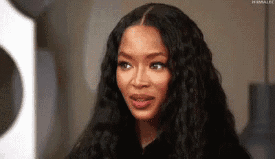 a woman with long black hair is making a funny face while looking at the camera .