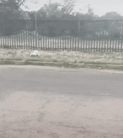 a man in a black shirt is dancing in the rain on a street .