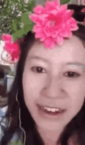 a woman with a pink flower on her head is smiling and wearing headphones .