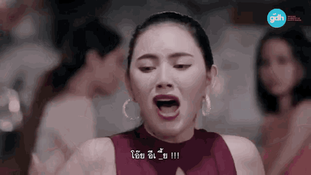 a woman in a red dress is making a funny face with her mouth open in front of a group of women .