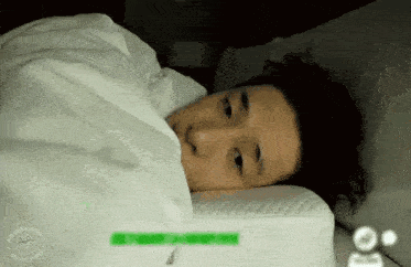 a man is laying in bed under a white blanket .
