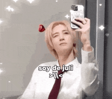 a man in a tie is taking a selfie with a cell phone .
