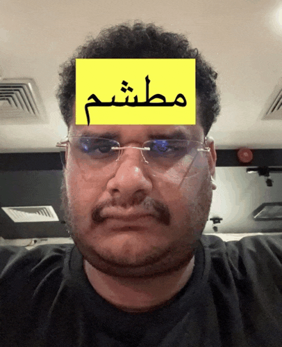 a man with glasses and a mustache has a yellow sign on his forehead that says ' muthm '