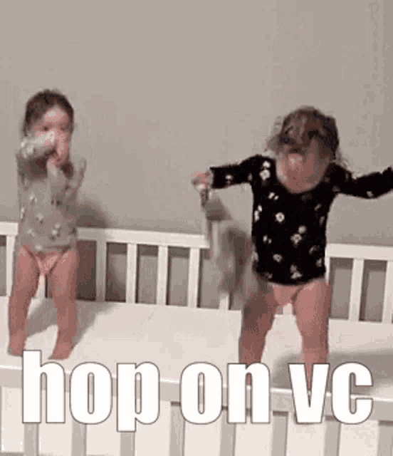two little girls are jumping in a crib with the words `` hop on vc '' written on the crib .