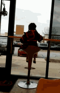 a person standing on a bar stool in front of a window with a sign that says boss