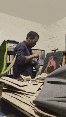 a man in a purple sweater is working on a painting in a room