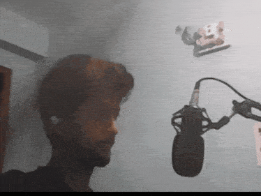 a man with a beard is singing into a microphone in a room