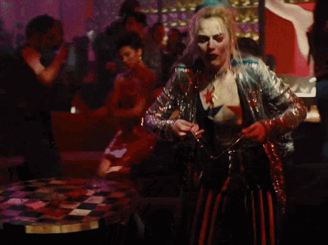 a woman in a sequined jacket and striped pants is dancing in front of a crowd