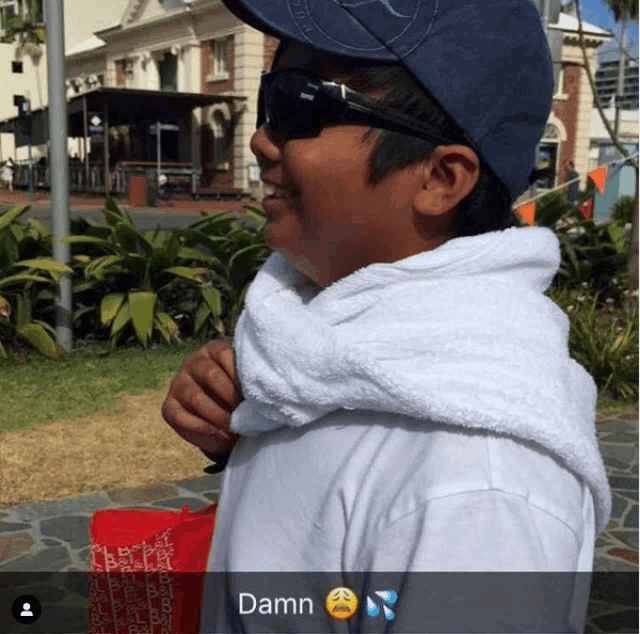 a boy wearing sunglasses and a towel around his neck says damn on the bottom