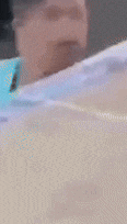 a blurry picture of a man 's face with a blue shirt and a necklace .