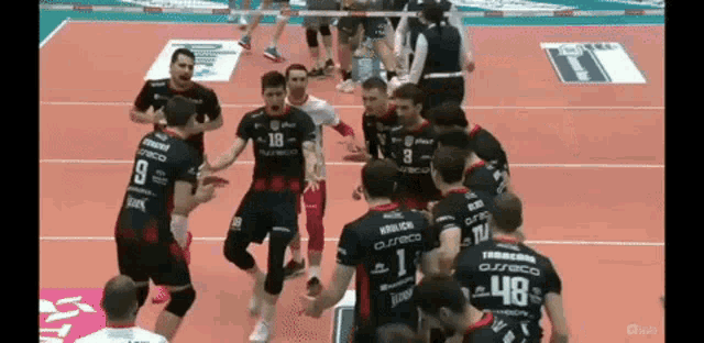 a group of volleyball players on a court with one wearing the number 18