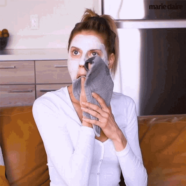 a woman with a mask on her face is holding a towel over her mouth
