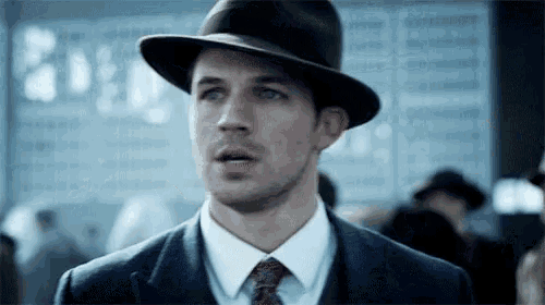 a man in a suit and hat is looking at the camera .
