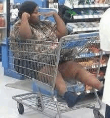 a man is sitting in a shopping cart with his legs crossed in a store .