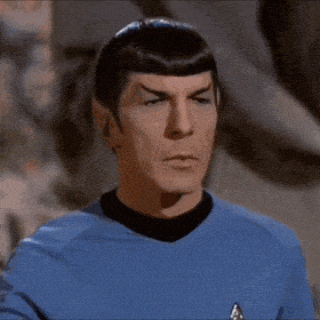 a close up of a man in a blue shirt making a stop gesture .
