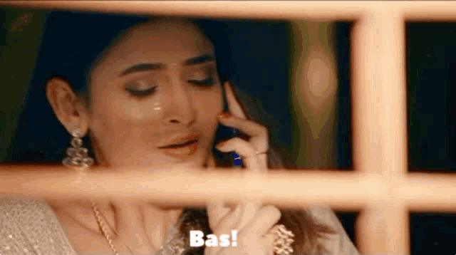 a woman is talking on a cell phone and the word bas is on the bottom right