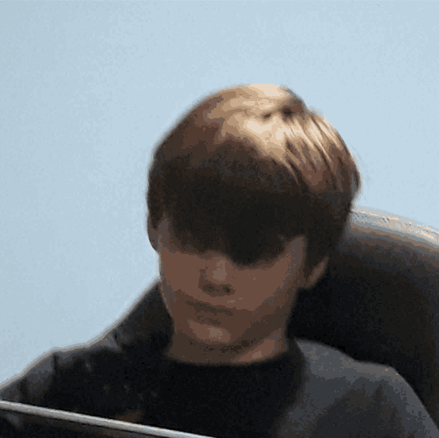 a young boy in a black shirt is sitting in a chair looking at a tablet