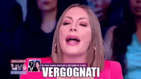 a woman in a pink jacket is making a funny face on a television show .