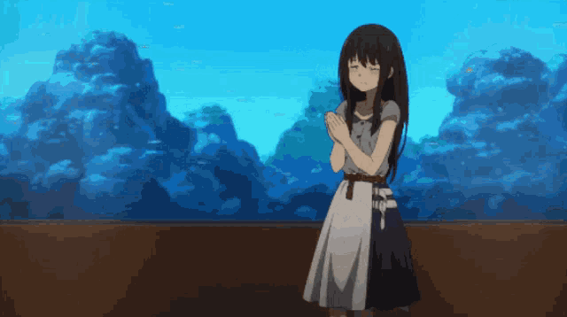 a girl stands in front of an aquarium with her hands together