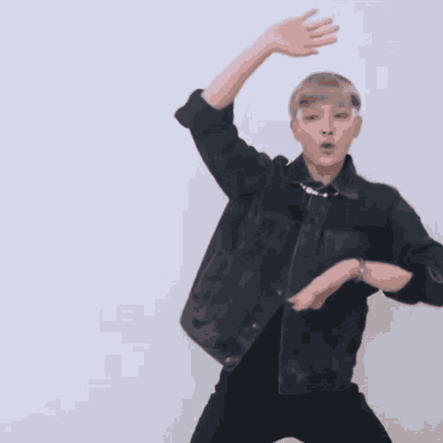 a man wearing a black denim jacket and black pants is dancing .