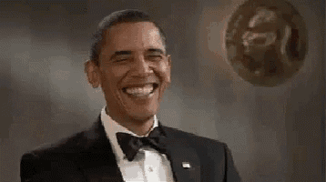 barack obama is wearing a tuxedo and bow tie and smiling while a balloon is flying in the background .