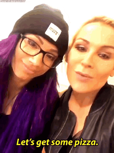 two women with purple hair and glasses are posing for a picture and one of them says let 's get some pizza