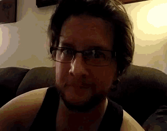a man with glasses is sitting on a couch