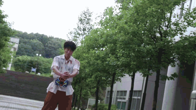 a man with blood on his shirt and pants is standing in front of a building