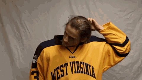 a man in a yellow west virginia jersey with the number 3 on it