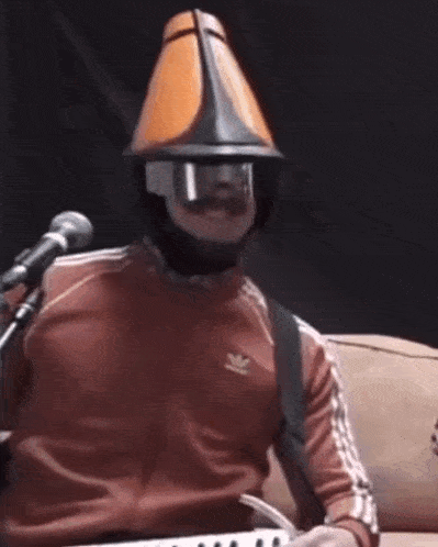 a man wearing a mask and a cone hat is playing a keyboard .