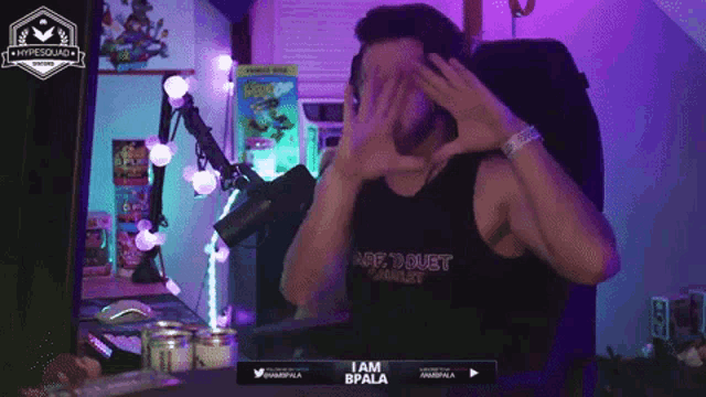 a man wearing a black tank top that says i am bpala covering his face