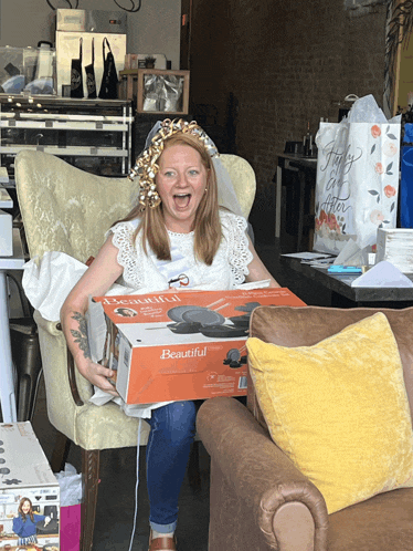 a woman is sitting in a chair holding a beautiful box