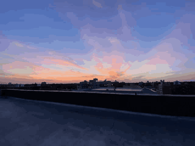 a rooftop view of a city with a sunset in the background