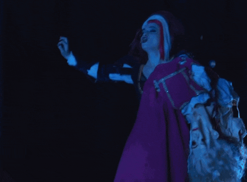 a woman in a purple dress is holding a puppet