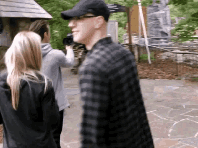 a man in a plaid shirt is walking with two women