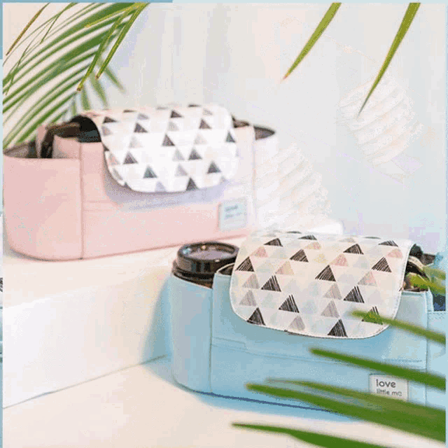 a pink and a blue purse with triangles on them are on a table