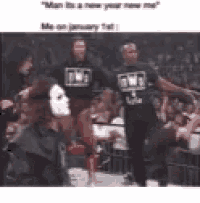 a man in a mask is standing in front of a crowd wearing a nwo shirt .