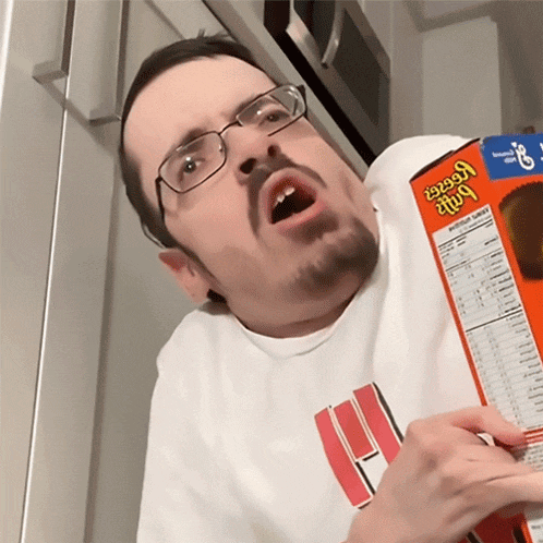 a man with glasses is holding a box of reeses peanut butter cups